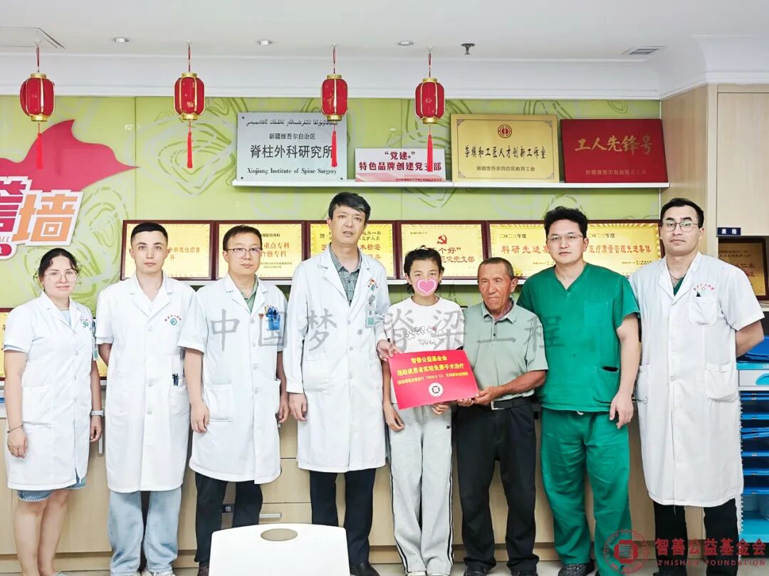 90 新疆医科大学第六附属医院阿不都乃比·艾力主任（左四）和医生（左起）阿吉古丽、麦麦提艾力、朱旭、马俊毅、尔帕尼江将智善公益基金会捐赠的18466.13元转交给新疆吐鲁番市患者阿伊谢（该患者实现免费治疗）.jpg