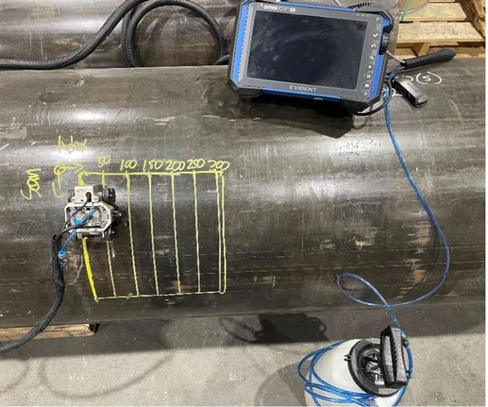 HydroFORM phased array scanner and OmniScan flaw detector positioned on a pipe with raster scanning lines drawn on it.